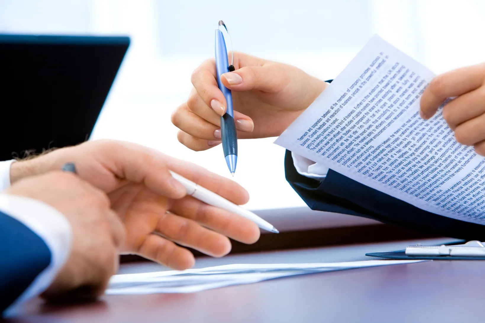 Two professionals engaged in a formal agreement, signing essential documents at a table.