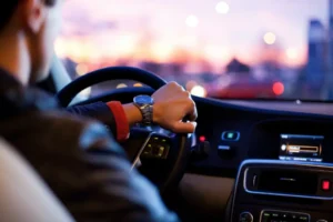 A man driving a car at night, firmly gripping the steering wheel, focused on the road ahead.